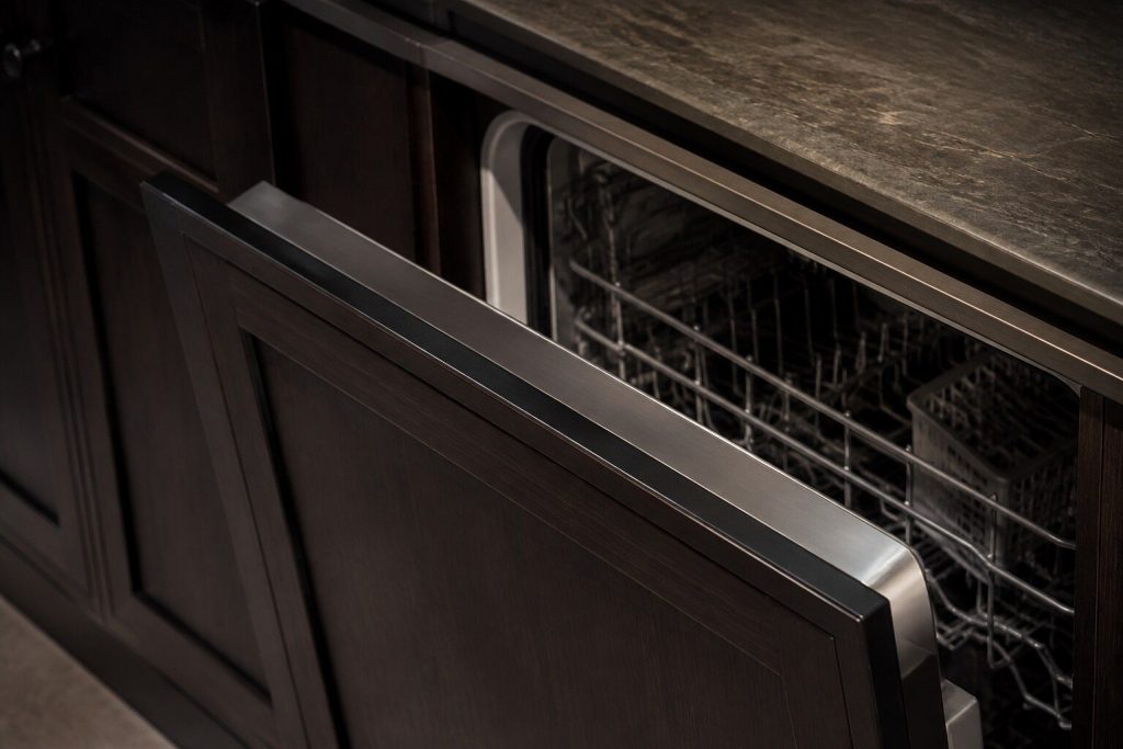 The top edge of an open integrated dishwasher door seen from above at a shallow angle, the flat control strip running along it.